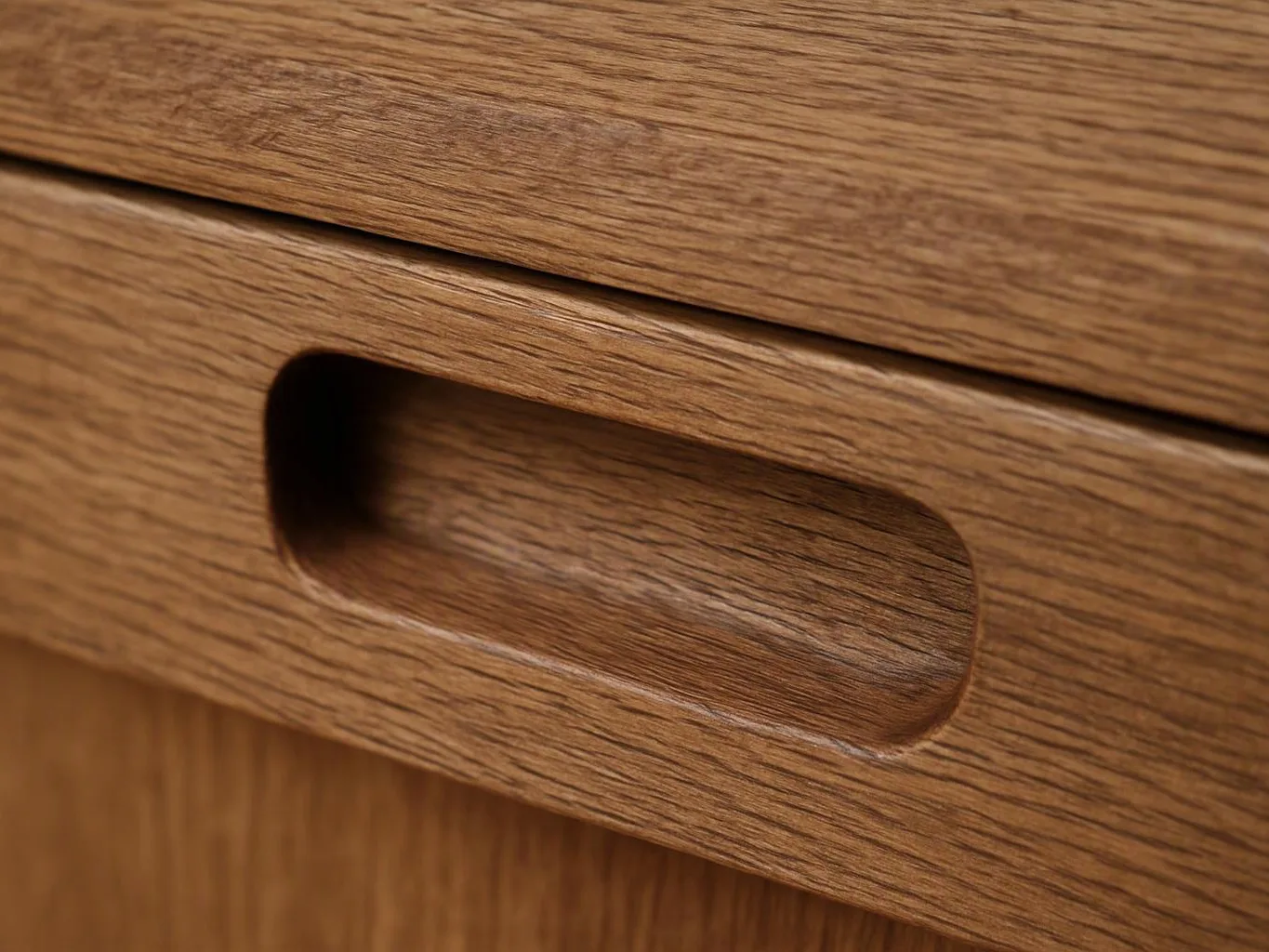 Close-up of a wooden drawer with a recessed handle and visible grain texture